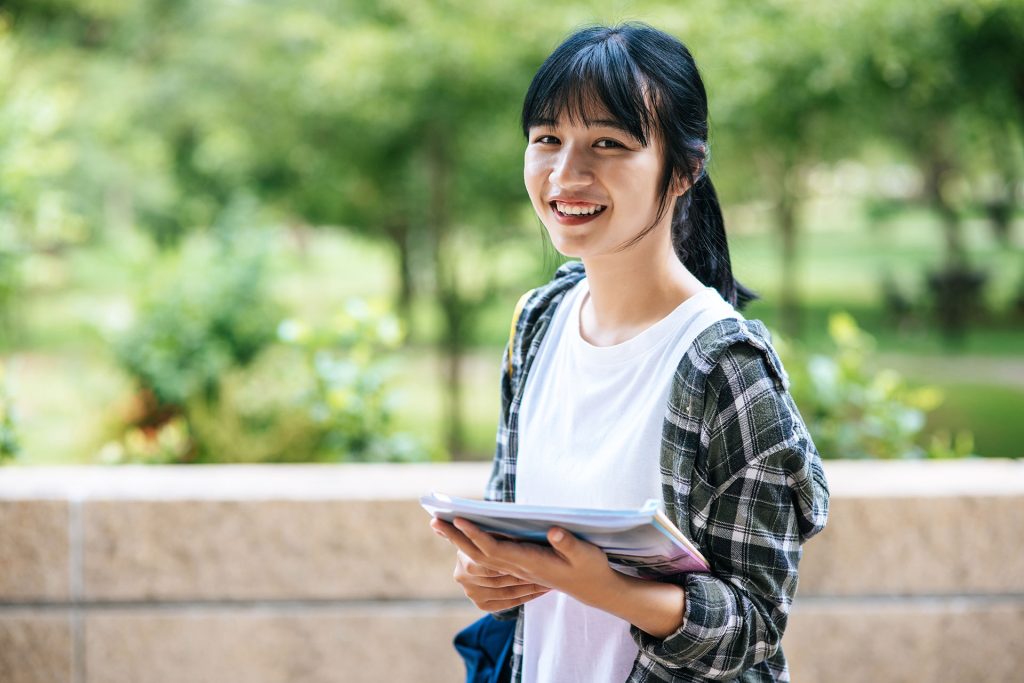 Asian student standing with book in hand