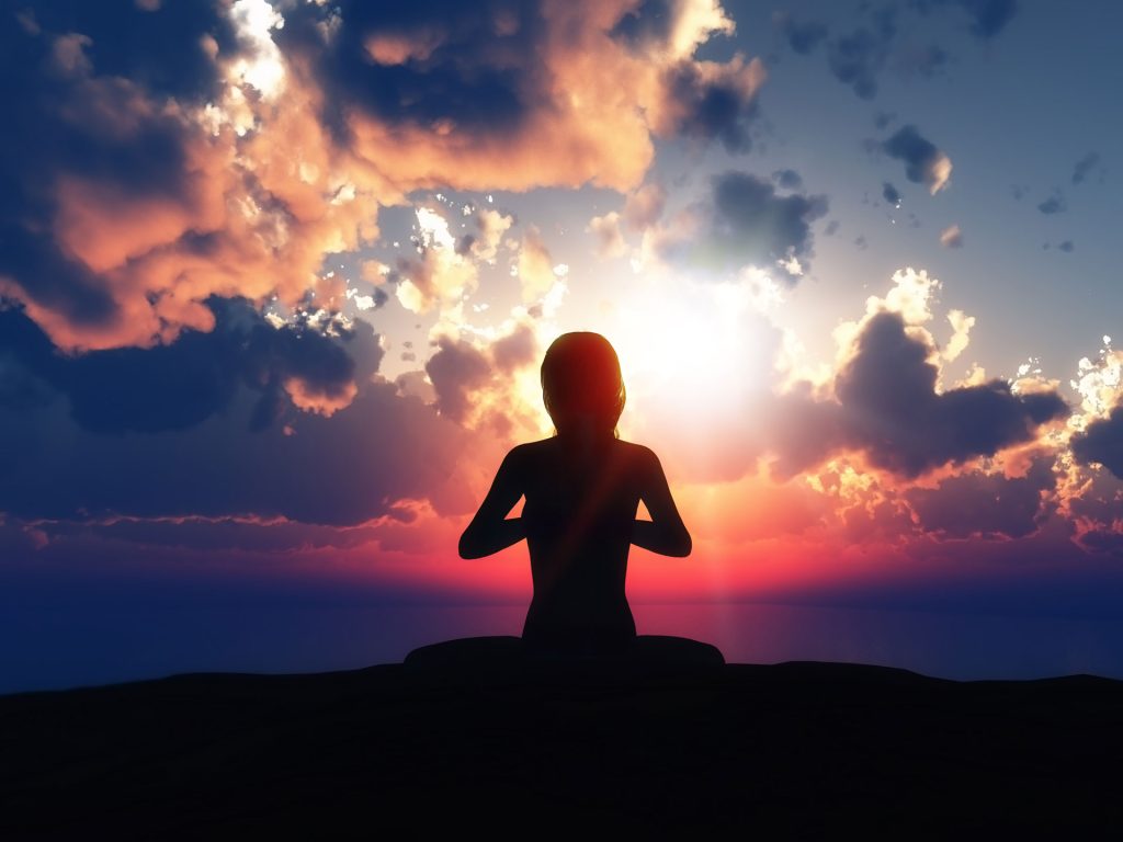 meditative yoga pose silhouette in front of cloudy sunset