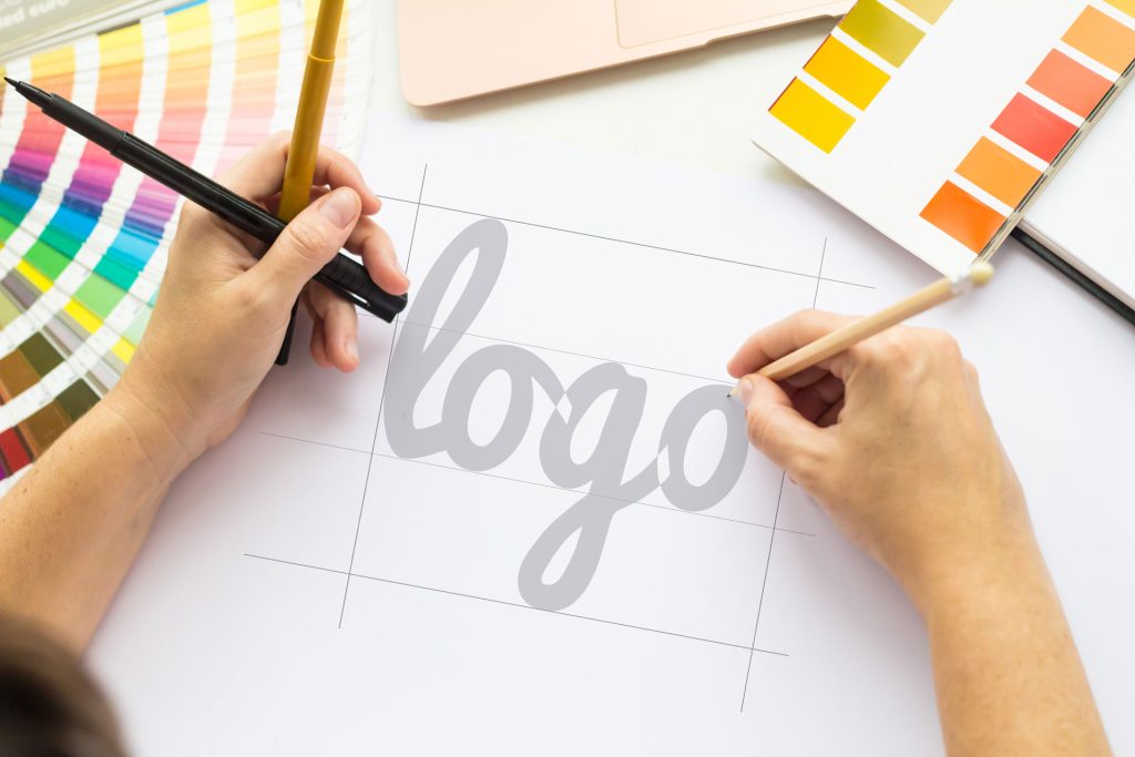 Designer at work on a logo with pencils and color charts
