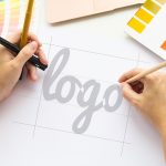 Designer at work on a logo with pencils and color charts